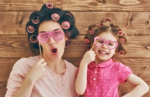 Funny family! Mother and her child daughter girl with a paper accessories. Beauty funny girl holding paper glasses on stick. Beautiful young woman holding paper glasses on stick.